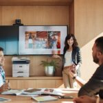 Xerox® B305 Multifunktionsdrucker in Arbeitssituation Lächelndes Arbeitsteam vor einem Bildschirm neben einem Xerox® B305-Multifunktionsdrucker