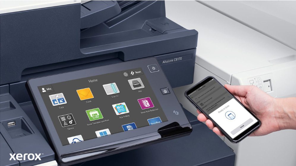 Eine Nahaufnahme der Hand einer Person, die ein Smartphone hält, das drahtlos mit dem Touchscreen-Bedienfeld eines Xerox-Multifunktionsdruckers verbunden ist und die nahtlosen mobilen Druck- und Scanfunktionen von Xerox ConnectKey demonstriert.